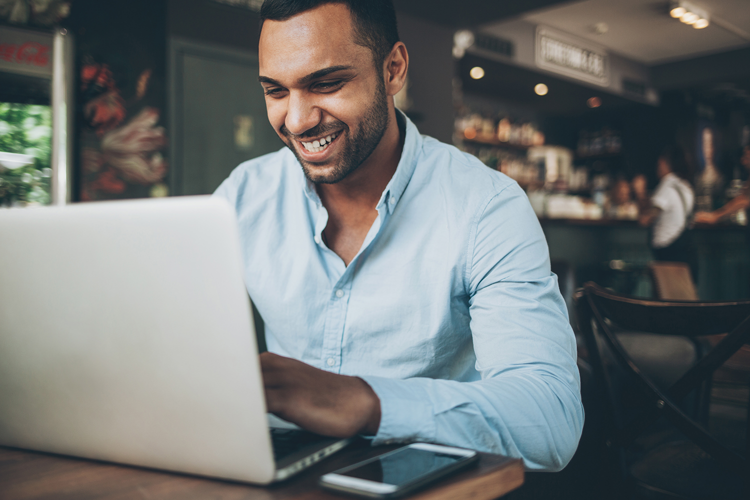 man in cafe on computer smiling