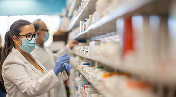 Pharmacist looking at medications on shelves